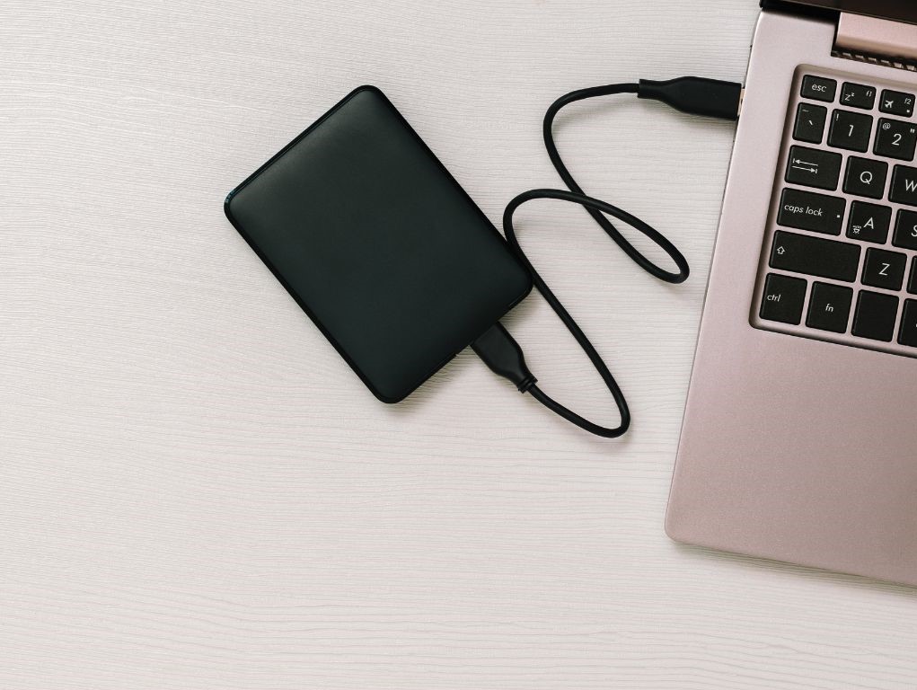 Pink laptop with mobile hard disk lying on a desk